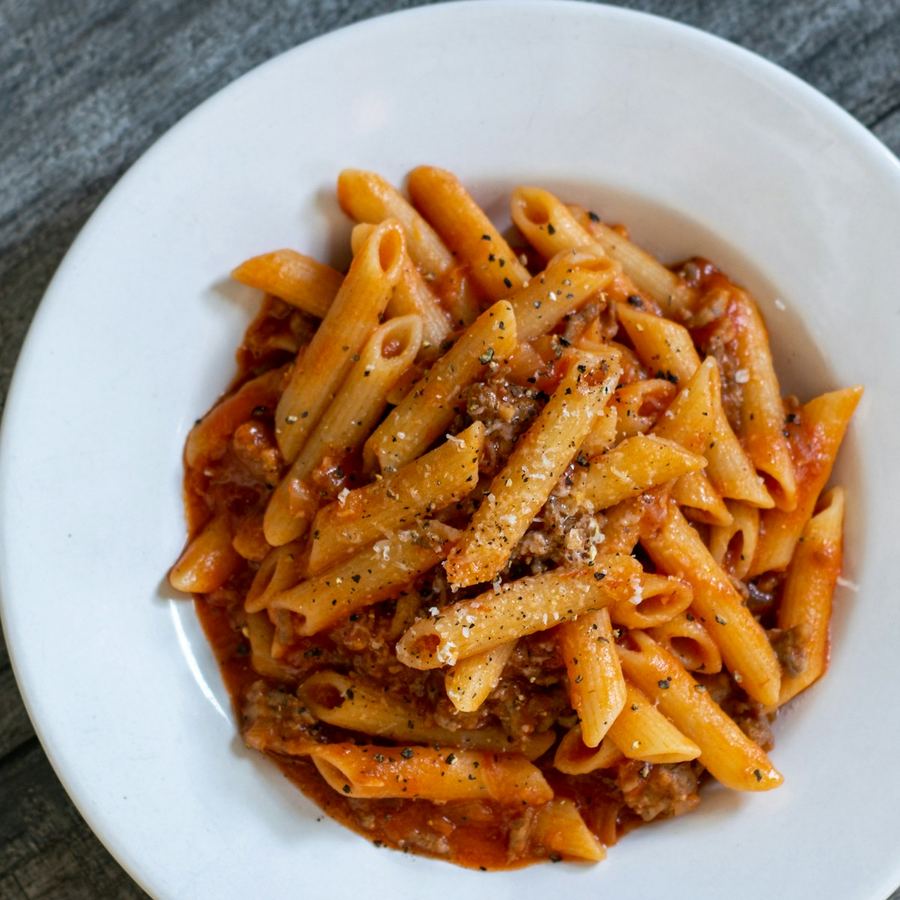 Piatto di penne al ragù con formaggio grattugiato