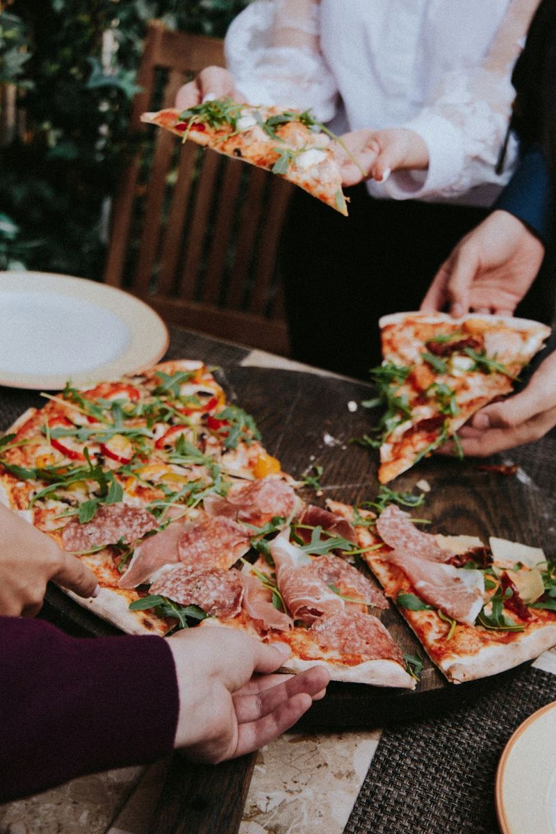 Amici attorno a un tavolo che si dividono pizze appena servite